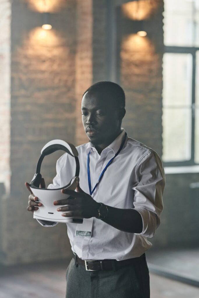 Man examining virtual reality headset in light-filled industrial setting.