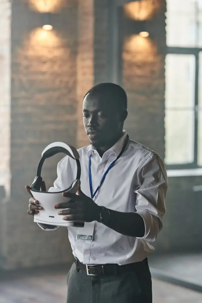 Man examining virtual reality headset in light-filled industrial setting.